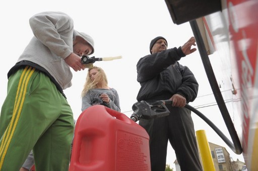 FUEL SHORTAGE. An attendant fills gas canisters as people wait in line at a Shell gas station on November 2, 2012 in Matawan, New Jersey. According to AAA, 60 % of gas stations in New Jersey are or were closed due to Superstorm Sandy. Michael Loccisano/Getty Images/AFP