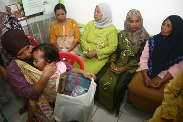 TRASH FOR TREATMENT. An Indonesian woman holds her child, seen at left, and a bag of recyclable garbage and others wait for consultation at Klinik Bumi Ayu in Malang in the main island of Java. There are five such centers in the city that are part of a scheme dubbed "Garbage Clinical Insurance" by its 24-year-old founder Gamal Albinsaid, offering treatment and advice for free to some of the country's poorest. Photo by Aman Rochman/AFP