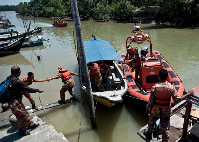 SEARCH AND RESCUE. A Malaysian search and rescue team disembarks from a boat after returning from a rescue mission on the outskirts of Banting on June 18, 2014, after an apparently overloaded boat carrying Indonesian illegal migrants sank overnight in seas off western Malaysia. Photo by Manan Vatsyayana/AFP