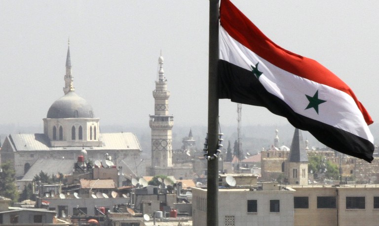 The Syrian flag flutters above Damascus on September 20, 2012. AFP PHOTO/LOUAI BESHARA