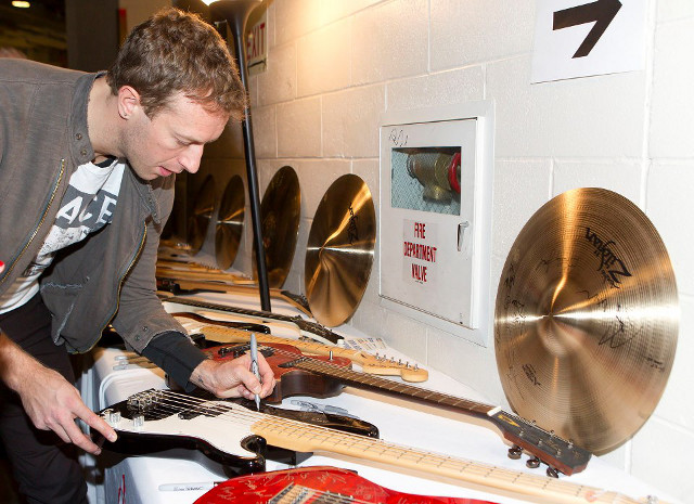 EVERY SIGNATURE HELPS. Coldplay's Chris Martin signs a guitar for the 121212 Concert auction. Photo from the official 121212 Concert Facebook page