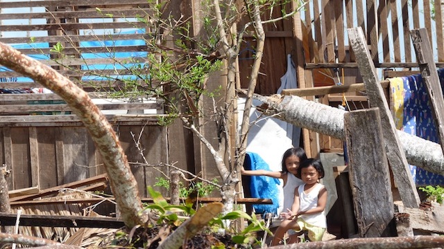 NO ROOF. The two kids of Mary Ann Cabunyas stand by what is left of their home.