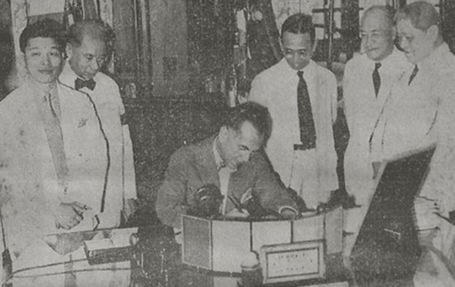 The Proclamation of the National Language being signed in the Presidential Study, Malacañan Palace. National Language Institute officials Cecilio Lopez (Tagalog), Jaime C. de Veyra (Samar-Leyte Visayan), Santiago A. Fonacier (Ilocano), Rafael Palma (Chairman of the National Council of Education), and Casimero F. Perfecto (Bicol), witness the signing.