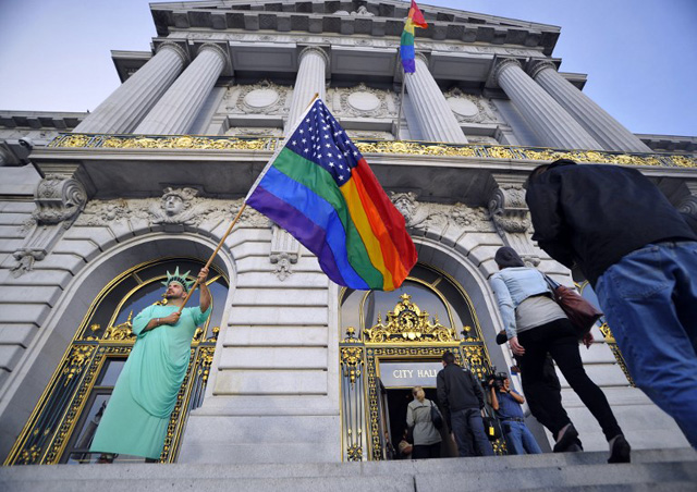 LANDMARK CASE. Nikolas Lemos waves a rainbow flag as people enter San Francisco City Hall in anticipation of The US Supreme Court ruling on gay marriage on June 26, 2013. Photo by AFP/Josh Edelson