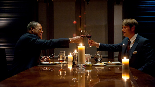 DRINK AND BE MERRY, FOR TOMORROW… FBI boss Jack Crawford (Laurence Fishburne) and Hannibal Lecter (Mads Mikkelsen) wine and dine 