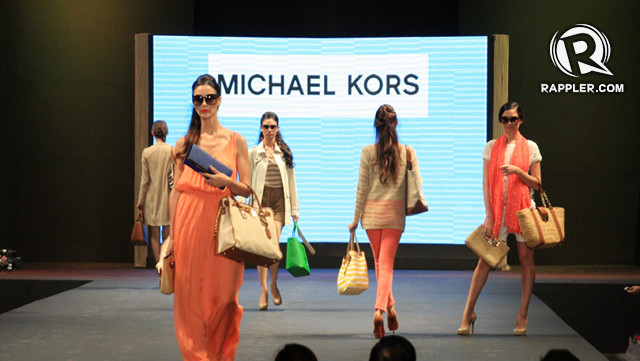 FAVORITE LOOK: SECOND FROM LEFT (BLUE CLUTCH). While Michael Kors provides a variety of summer bags, our favorite look is the small blue clutch bag paired with a salmon colored dress. 