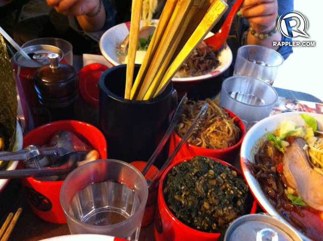 CROWDED TABLE. The cramped table for four with the entire tabletop occupied by soup bowls, condiments, drinks, and chopsticks
