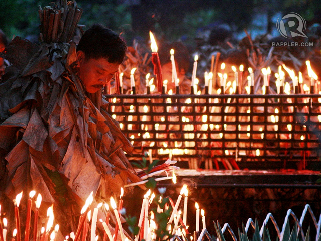LIT PRAYERS. A devotee lights a candle, a symbol of an intention or prayer offered 