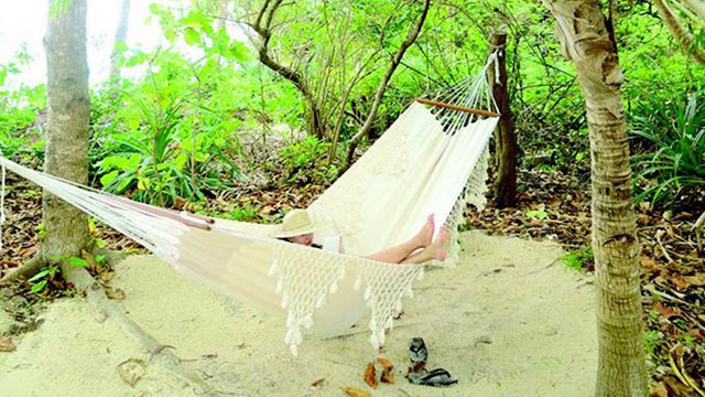 PRIVATE PARADISE. The author while in Amanpulo, reading a book in a hammock between the casita and a private beachfront. Photo by Lisa Cruz