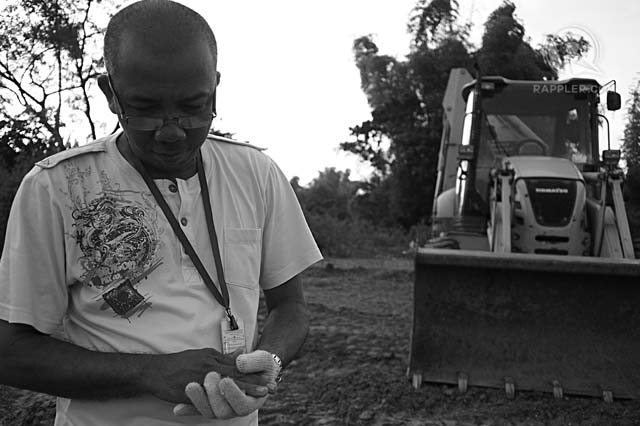 A PRAYER FOR THE DEAD. Ariel Malicay, Heavy Equipment Operator 1, offers his respects before a Mercedes mass grave. 26 Sep 2013 Photo by Paolo Villaluna