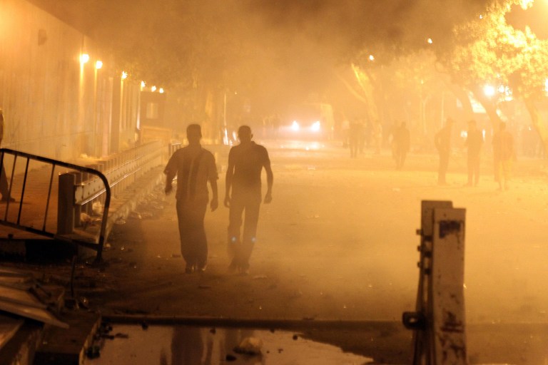 CAIRO VIOLENCE. Egyptian men walk amidst smoke following clashes between protesters and Egyptian police near the US embassy in Cairo early on September 13, 2012. Police used tear gas as they clashed with a crowd protesting outside the US embassy in Cairo against a film mocking Islam, images broadcast by Egypt's public television showed. AFP PHOTO/ AHMED MAHMUD