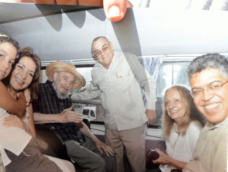 An image of former Cuban President Fidel Castro (3-L) is held up by former Venezuelan Vice-President Elias Jaua in La Havana on October 21, 2012. The photograph shows the former Cuban leader alongside Jaua (R), as well as Cuban National Hotel director, Antonio Martinez (C), Castro´s wife, Dalia Soto del Valle (2-R), and an unidentified woman and child. According to Jaua, Castro conversed with him for many hours and is in very good health. AFP PHOTO/ADALBERTO ROQUE