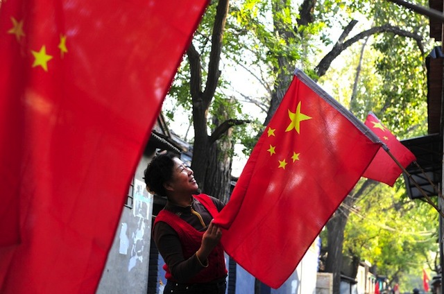NATIONALISM. This picture taken on August 27, 2012, shows a resident hanging a Chinese national flag outside her home ahead of the 18th China Communist Party Congress in Beijing. AFP PHOTO