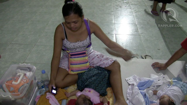 SLEEPLESS. Neaville Patata takes care of her 3-month old son, foregoing sleep at an evacuation center in Rosario, Cavite while they wait for floods to subside. All photos by David Lozada/Rappler