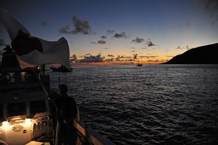 DISPUTE. A boat - part of a flotilla of ships carrying some 150 people, including eight parliamentarians - is silhouetted at sunrise as it approaches a group of islands (R) known as Senkaku in Japanese and Diaoyu in Chinese, early on August 19, 2012. AFP PHOTO / Antoine Bouthier