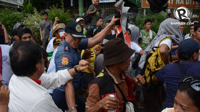 NO PLACARDS. A police officer rips apart one protester's placard at the EDSA Tayo "prayer vigil." Photo by Mark Demayo