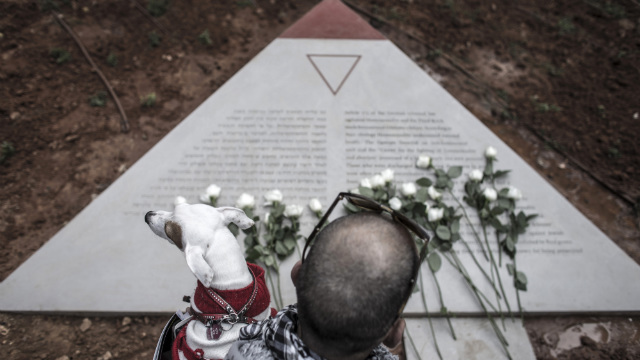 MONUMENT. A man embraces his dog after he laid down a rose on a new monument commemorating jewish and non-jewish people who died under the Nazi-regime due to their sexuality. Photo by Oliver Weiken/EPA