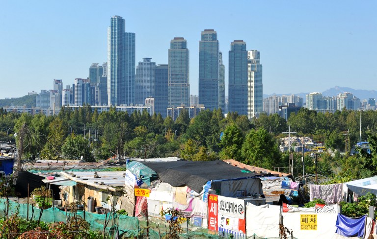 This photo taken on October 11, 2012 shows highrise business buildings towering in the background over Guryong, a shanty town near South Korea's wealthiest Gangnam district in Seoul. Guryong -- a squalid, sprawling slum of plywood and tarpaulin shacks settled in 1988 by squatters evicted from other areas in a push to beautify Seoul as it prepared to host the Olympic Games. Nearly 25 years later, Guryong (which translates as "Nine Dragons") has more than 2,000 residents scrabbling out a subsistence living with Third World poverty levels and little or no proper sanitation. AFP PHOTO / KIM JAE-HWAN