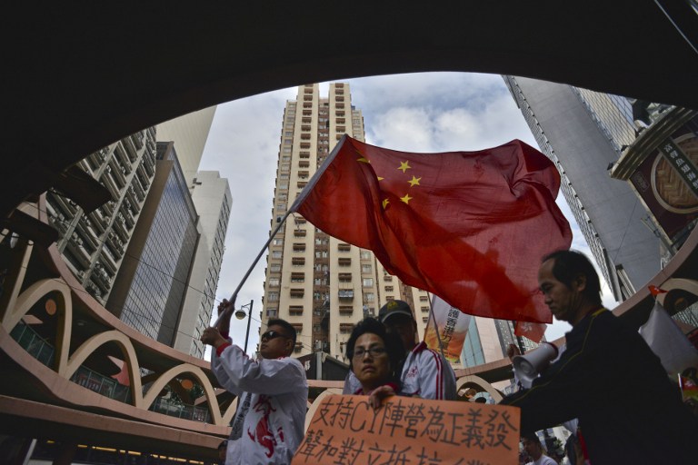 Marchers referring to themselves as supporters of Hong Kong and of the city's leader, Leung Chun-ying, walk with a Chinese flag though the streets of Hong Kong on December 30, 2012. AFP PHOTO / ANTONY DICKSON