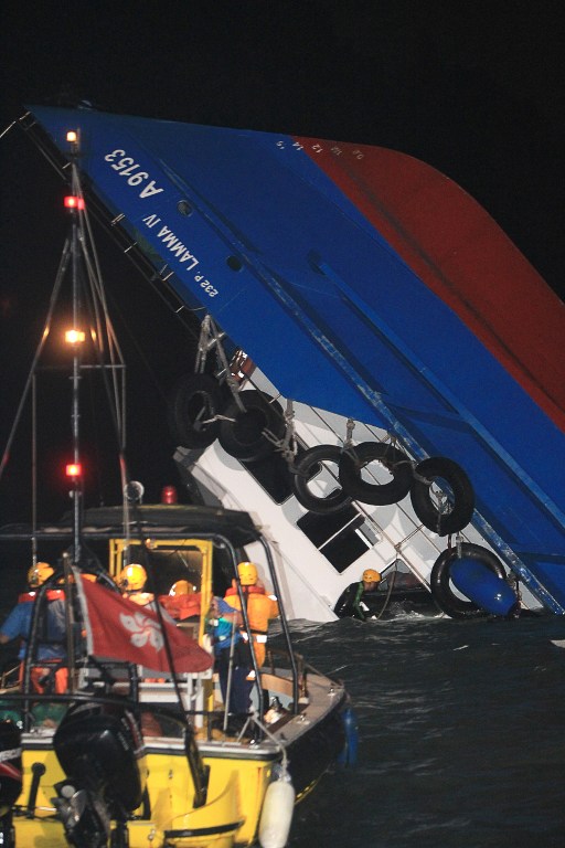 FERRY ACCIDENT. A rescuer looks through a door of a rapidly sinking ship after a collision between a ferry and another boat killed eight people and injured 45 others off Hong Kong late on October 1, 2012. - AFP/Apple Daily