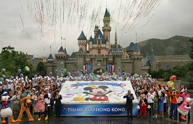 FINALLY PROFITABLE? The management and staff of Hong Kong Disneyland wave next to a giant birthday cake to mark the theme park's first anniversary in Hong Kong last 12 September 2006. But only 7 years after--this 2012--that the venture turns profitable, a report says. Photo by AFP 
