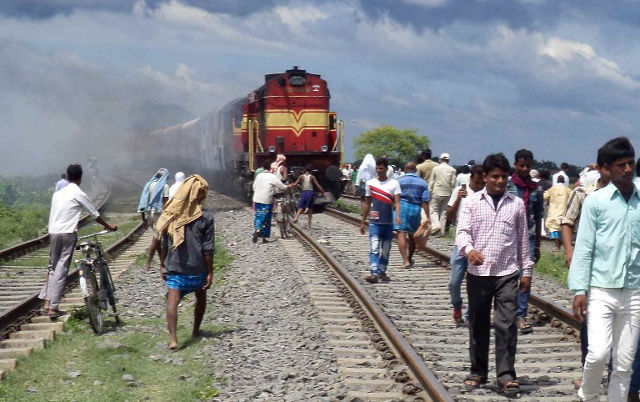 TRAIN ACCIDENT. Indians walk on railroad tracks as train coaches of the Rajya Rani Express, set on fire by an angry mob, burns after the train ploughed into a crowd of Hindu pilgrims at the Dhamara Ghat railway station in Khagaria district, some 248 kilometres (154 miles) from Bihar state capital Patna, on August 19, 2013. An Indian express train ploughed into a crowd of Hindu pilgrims in the country's east on August 19, killing 37 and triggering a riot that left one of the drivers dead, an official said. AFP PHOTO