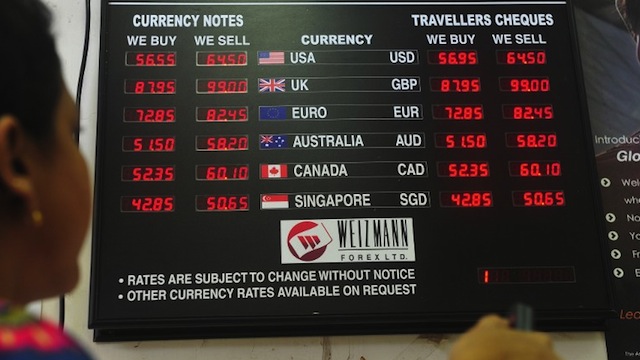 An employee works next to a board showing the exchange rate of Indian rupees to other currencies at a foreign exchange dealer in Mumbai. AFP PHOTO/ INDRANIL MUKHERJEE