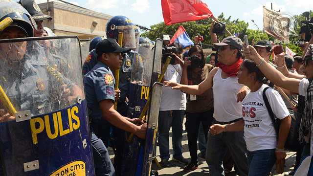 VIOLENT CLASH. Policemen block the entrance of the Quezon City hall on Monday, July 1, as protesters tried to break through. Photo by Mark Demayo.
