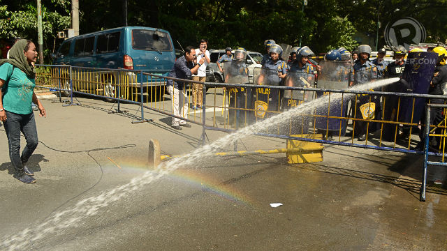 BRUTE FORCE. Policemen use water cannons to keep the protesters from entering the Quezon City hall. Photo by Mark Demayo.