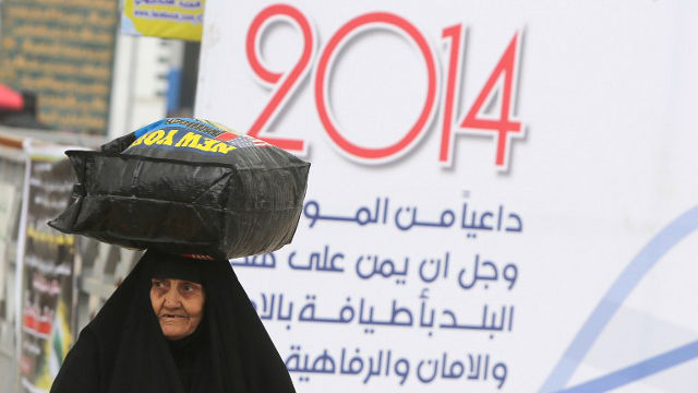 NEW YEAR.  An Iraqi woman carries a load on her head on New Year's day in the capital Baghdad, January 1, 2014. Ahmad Al-Rubaye/AFP Photo