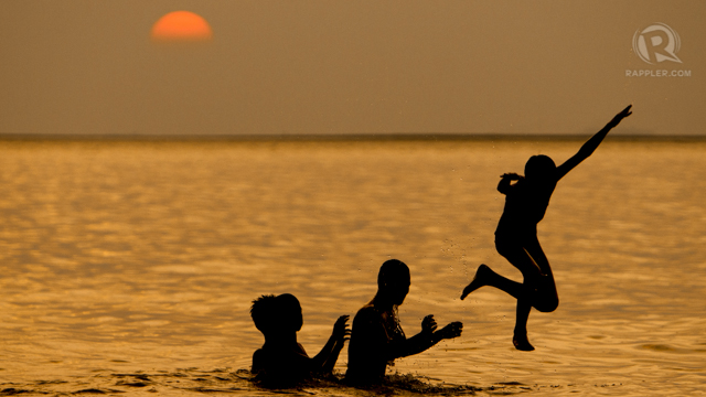 People bask in the polluted waters of Manila Bay to beat the summer heat.