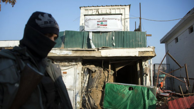 SUICIDE ATTACK. An Afghan policeman stands guard next to the damaged entrance of a Lebanese restaurant that was attacked in Kabul, on January 18, 2014. At least 21 have died from the attack. Photo by AFP