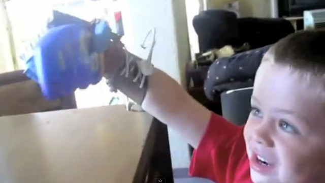 ROBOHAND. Liam grabs a bottle with his new prosthesis. Screen shot from YouTube video.
