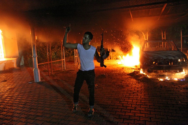 An armed man waves his rifle as buildings and cars are engulfed in flames after being set on fire inside the US consulate compound in Benghazi late on September 11, 2012. AFP Photo 