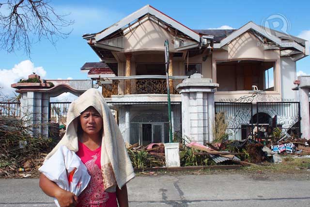 WE THE LIVING. Lynn Rose Logarte outside the house that saved over fifty people in Sto. Nino, Tanauan, Leyte. Photo by Jake Verzosa
