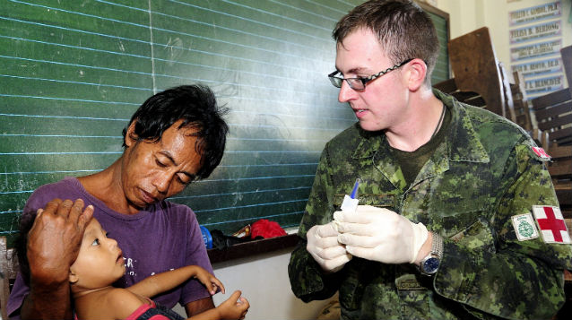 TO THE RESCUE. A Canadian medic checks on a child in an evacuation center outside of Roxas City, Capiz after Super Typhoon Yolanda (Haiyan). File photo from the Canadian embassy in Manila
