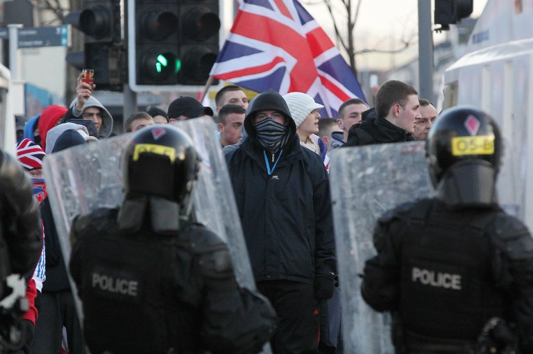 Police in riot gear try to contain with Union Flag waving loyalist protesters during clashes in east Belfast, Northern Ireland on January 12, 2013 after the latest loyalist march against the decision to limit the days on which the Union Flag would be flown over Belfast City Hall. AFP PHOTO / PETER MUHLY