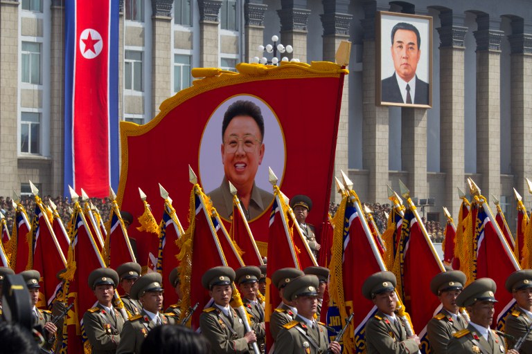 Portraits of former North Korean leaders Kim Jong-Il (L) and his father Kim Il-Sung (R) are displayed as soldiers march during a military parade to mark 100 years since the birth of the country's founder Kim Il-Sung in Pyongyang on April 15, 2012. AFP PHOTO / Ed Jones 