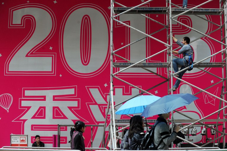 PREPPING FOR 2013. A worker (top R) climbs up a scaffolding support in front of a promotional 2013 banner ahead of the new years eve celebrations outside a shopping mall in Hong Kong on December 29, 2012. AFP PHOTO / ANTHONY WALLACE