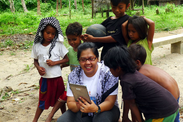 VOLUNTEER. Bing Pedolin, one of the community volunteers amuse the kids with her iPad. Photo by Henson Wongaiham