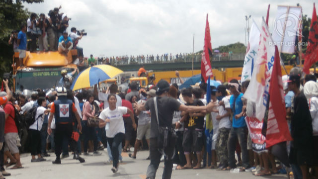 CROSSING THE LINE. Police clash with protestors who attempt to break the line in Commonwealth Avenue, Quezon City near where President Beningo S. Aquino III is to deliver his 4th State of the Nation Address. Photo by David Lozada/Rappler