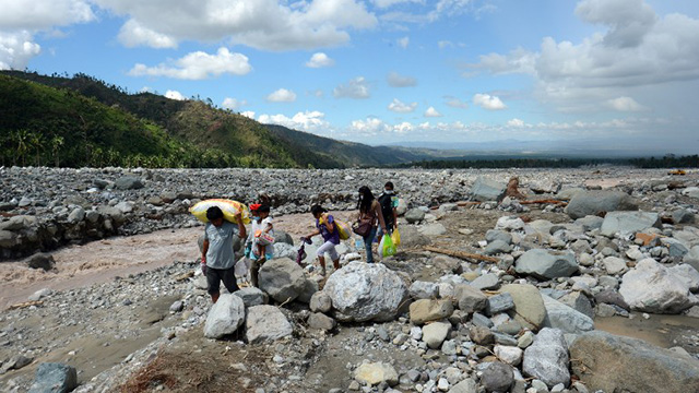 DEBRIS FIELD. A family carrying food relief for victims of Typhoon Pablo (Bopha) walks along a river as they head for home in the village of Andap in the town of New Bataan in the Compostela Valley province on December 8, 2012. AFP PHOTO / TED ALJIBE