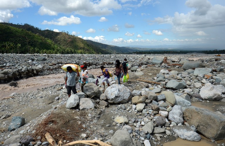 DEBRIS FIELD. A family carrying food relief for victims of Typhoon Pablo (Bopha) walks along a river as they head for home in the village of Andap in the town of New Bataan in the Compostela Valley province on December 8, 2012. AFP PHOTO / TED ALJIBE