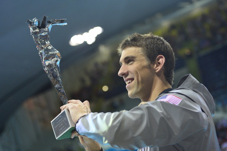 US swimmer Michael Phelps poses after he received the trophy of the greatest olympic athlete of all time after he won gold in the men's 4x100m medley relay final during the swimming event at the London 2012 Olympic Games on August 4, 2012 in London. AFP PHOTO / LEON NEAL