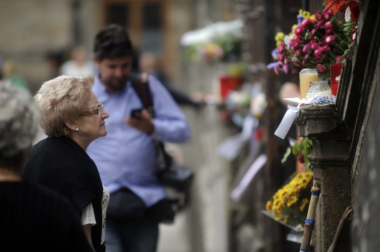 Seorang wanita melihat bunga dan lilin yang dipajang di pagar Katedral Santiago de Compostela untuk menghormati para korban kecelakaan kereta api di Obradoiro Square, di kota Santiago de Compostela, Spanyol utara, pada 27 Juli 2013.  Foto oleh RAFA RIVAS / AFP
