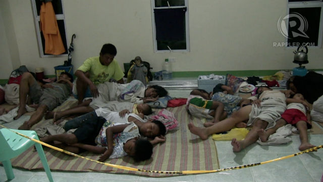 BEST OPTION. Families from Rosario, Cavite rest at the municipal hall after voluntarily evacuating their homes