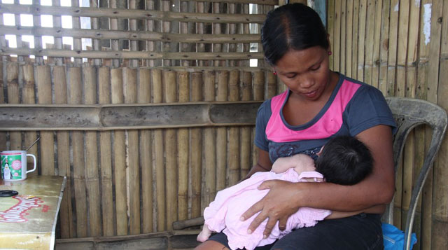 MOTHER'S MILK. May-Joy and her two week old daughter Ariana in their home which was destroyed by Typhoon Haiyan but has since been repaired, Panay Island, Philippines. Photo by Evan Schuurman/Save the Children