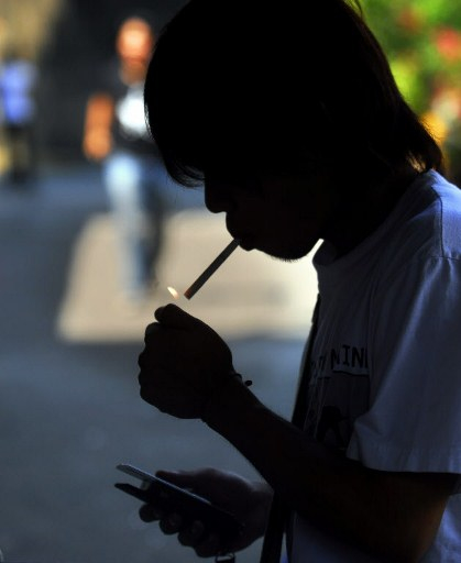 A student lights a cigarette near a school in Manila. Photo from AFP