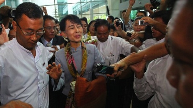 Myanmar opposition leader Aung San Suu Kyi (C) is surrounded by media representatives ahead of her departure at Yangon International Airport on June 13, 2012. AFP PHOTO/Ye Aung Thu