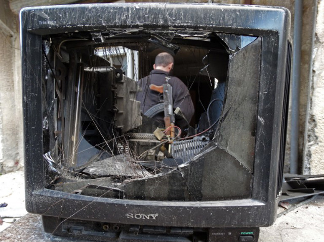 SYRIAN REBEL. A rebel fighter stands behind a broken television in the Salaheddin district of the northern Syrian city of Aleppo. Karam Al-Masri/AFP